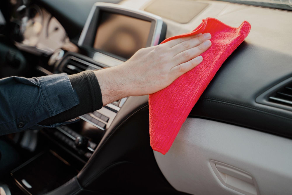 driver wipes the inside of a vehicle with a red microfiber cloth