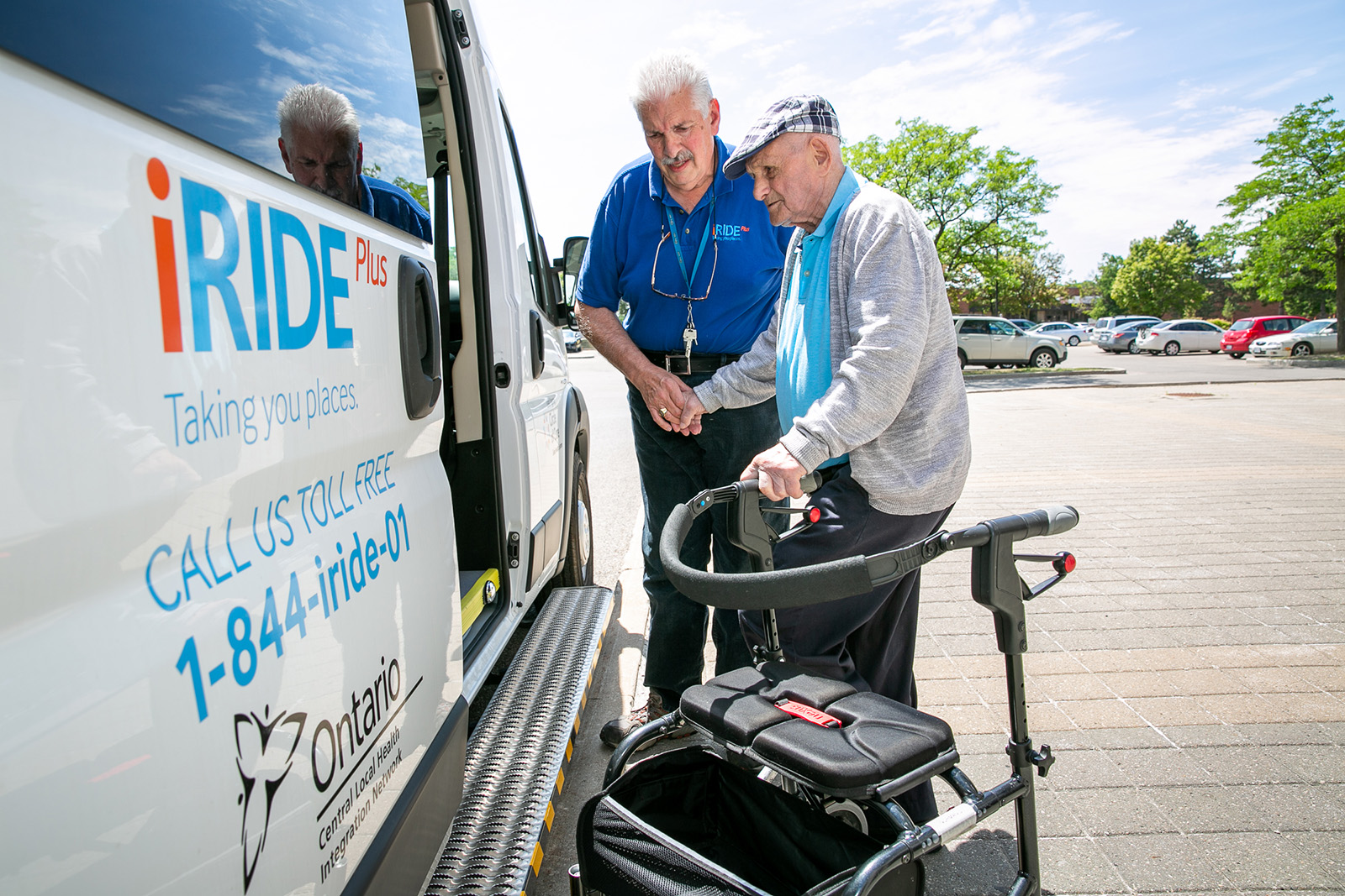 iRIDE driver assists a male client with a walker with getting into an iRIDE van